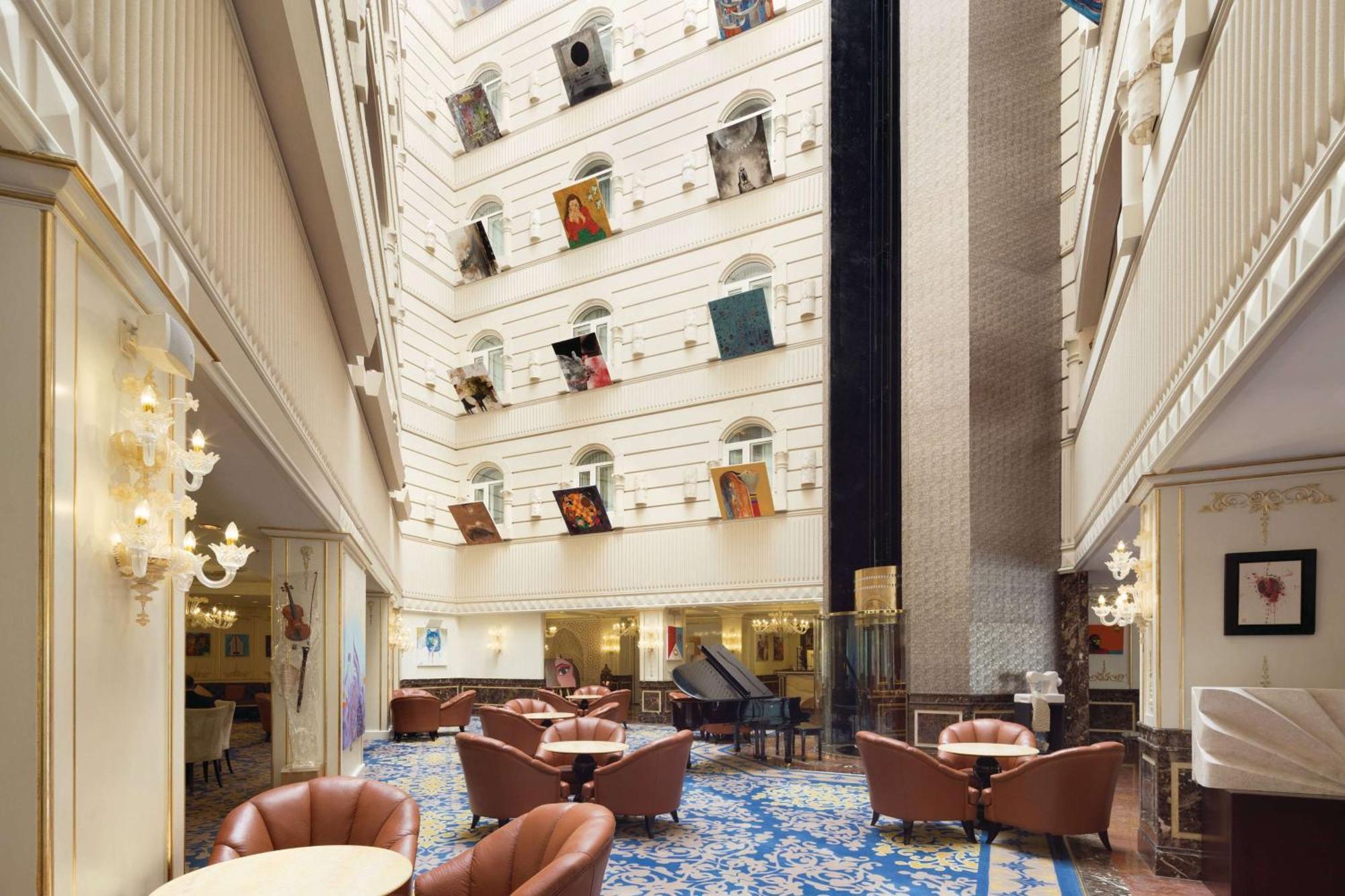 Grand Regency Doha, Trademark Collection By Wyndham Zewnętrze zdjęcie The photo depicts the interior of a spacious, upscale hotel lobby. The design features high ceilings and multiple levels, with large windows that create a bright and airy atmosphere. Elegant light fixtures adorn the walls, and the floor is covered wi