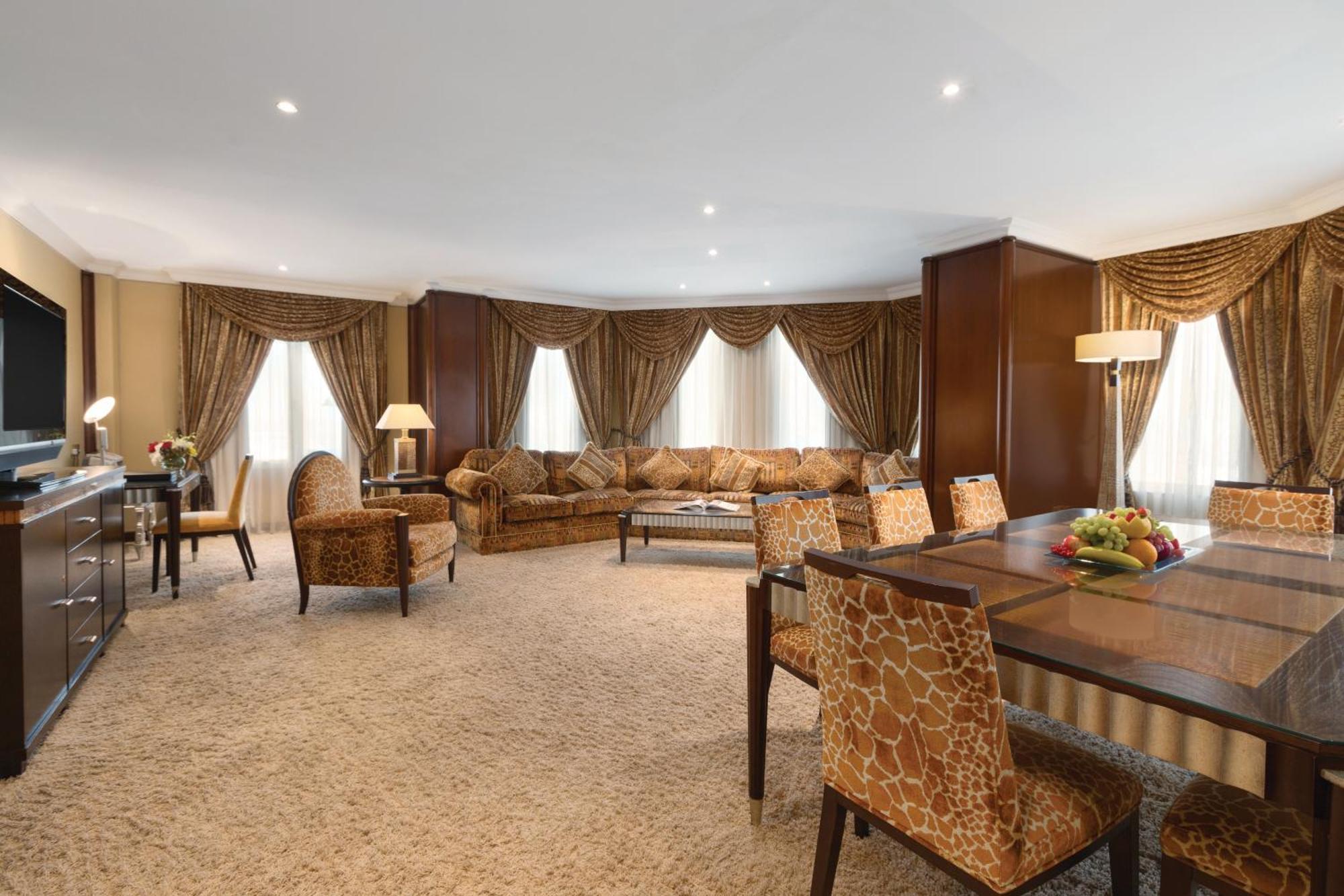 Grand Regency Doha, Trademark Collection By Wyndham Zewnętrze zdjęcie The photo shows a spacious and elegantly designed living area. There are large windows dressed with luxurious curtains, allowing natural light to fill the room. The seating arrangement features a comfortable sofa with various cushions and several sty