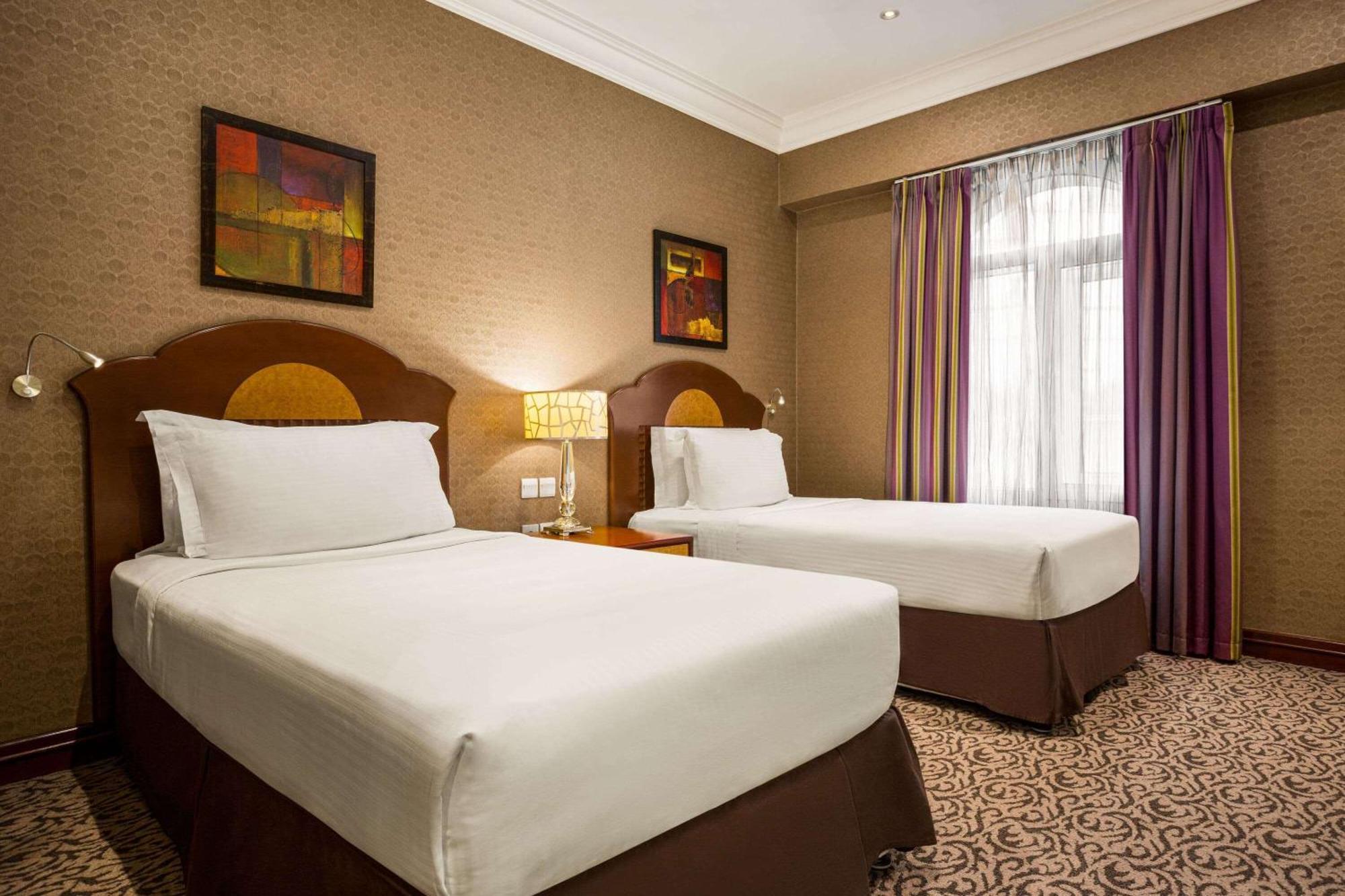 Grand Regency Doha, Trademark Collection By Wyndham Zewnętrze zdjęcie The photo shows a hotel room featuring two single beds with white bedding and dark brown upholstered headboards. There is a bedside table with a lamp between the beds. On the walls are two abstract paintings, and large windows dressed with sheer curt
